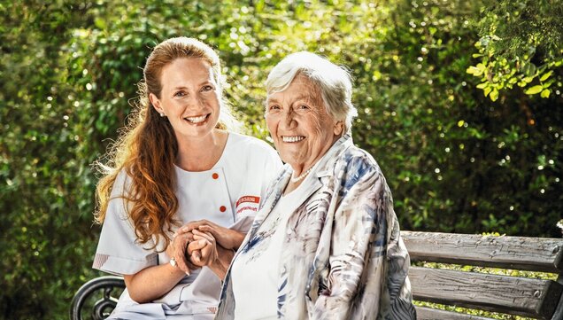 Caregiver sits with senior on a bench