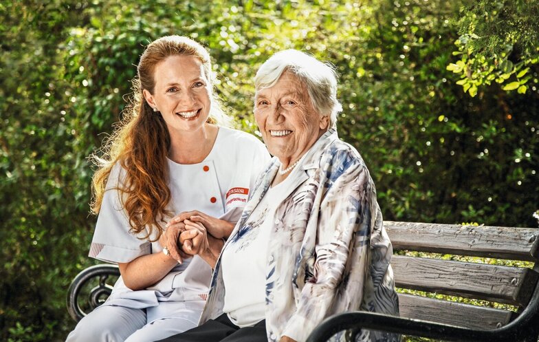 Caregiver sits with senior on a bench