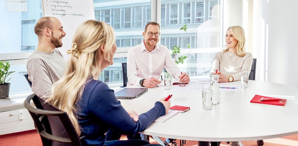 Four people in a meeting with flipchart and notes