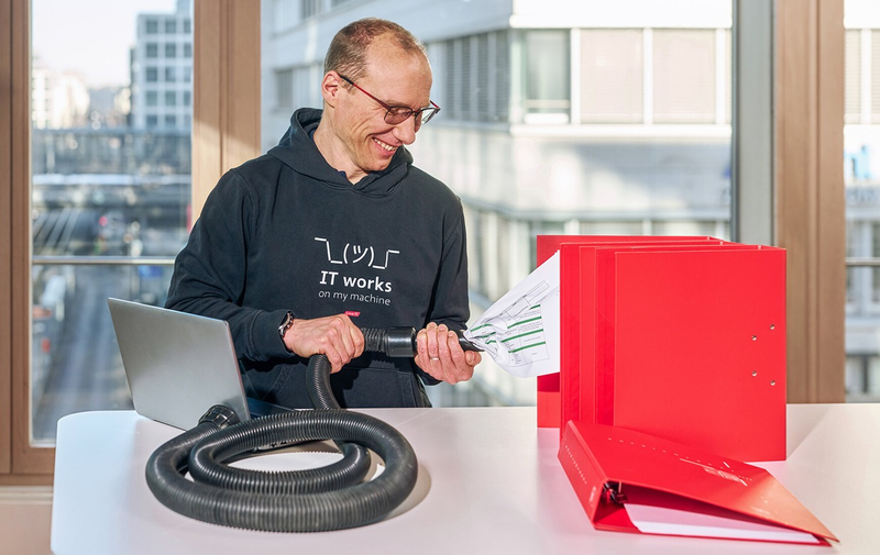 Person with a hose and red folders, symbolic representation of data management