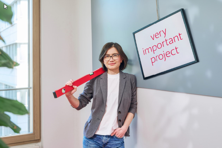 Person holding a red spirit level in front of a wall with project signage