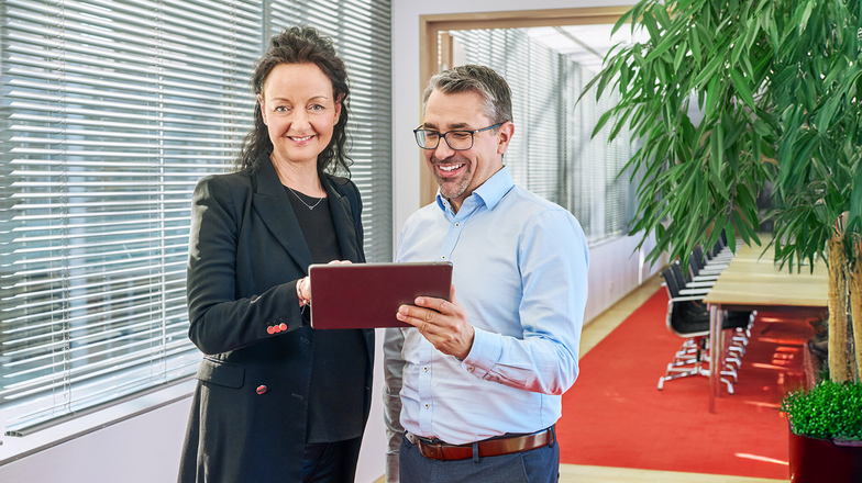 Two people looking at a tablet in a modern office