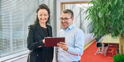 Two people looking at a tablet in a modern office