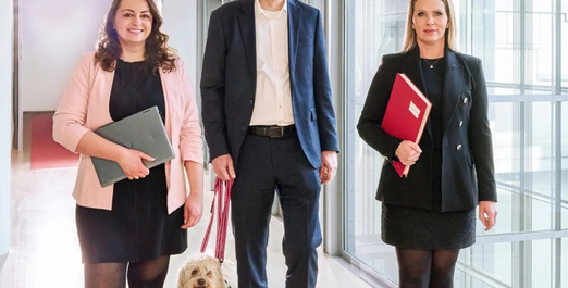 Three people walking through an office building with documents