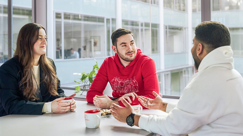 Discussion round with three people and coffee mugs