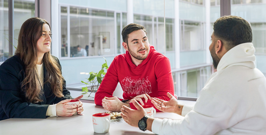 Discussion round with three people and coffee mugs