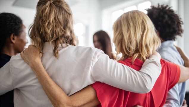 People stand in circle and hug each other 